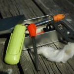 An emergency fire kit flat-lay featuring a ferro rod essential for the Canadian wilderness trail.