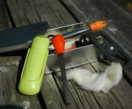 An emergency fire kit flat-lay featuring a ferro rod essential for the Canadian wilderness trail.